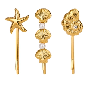 Détail de 3 barrettes dorées en forme d'étoile de mer et coquillage avec perles
