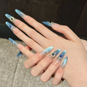Poseidon blue cat-eye stiletto nails with 3D crystal accents and floral gold charms