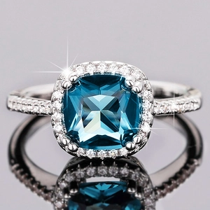 Macro shot of cushion-cut blue gemstone ring with a halo of white zircon and reflections