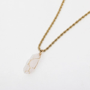 Detailed macro of gold wire wrapped hexagonal crystal pendant on a rope chain necklace
