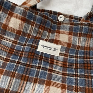 Detail of vintage blue brown plaid wool tote bag showing texture and magnetic closure