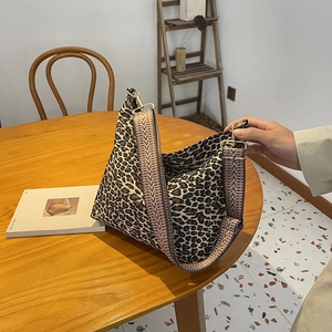 Chic leopard print canvas tote bag with wide shoulder strap on a wooden table