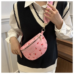 Detail of pink nylon crossbody bag featuring red cherry print and golden zipper