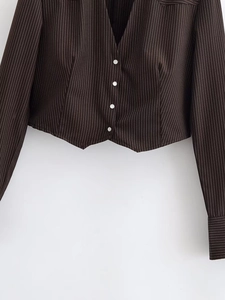 Detail of dark brown pinstripe short jacket showing white buttons and pointed hem