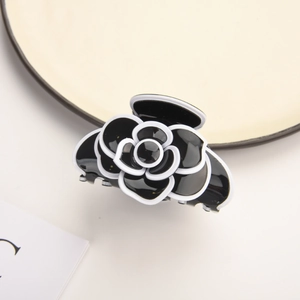 Detailed view of black camellia hair claw with white outline and acetate finish