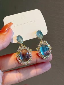 Detail of vintage mint blue cat-eye stone earrings with zircon in gold-tone setting