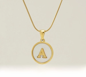 Macro shot of 18K gold plated stainless steel snake chain and shell letter A pendant
