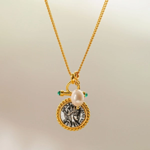 Detail of vintage gold necklace with medallion coin, white pearl and green gemstone
