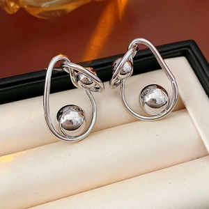 Macro shot of silver metallic twisted sphere earrings displayed in a beige velvet jewelry box