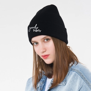 Close-up of a black beanie with white Good Vibes embroidery and folded cuff detail