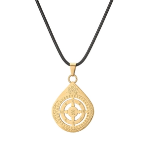 Macro detail of gold lotus drop pendant with religious engravings and black woven cord