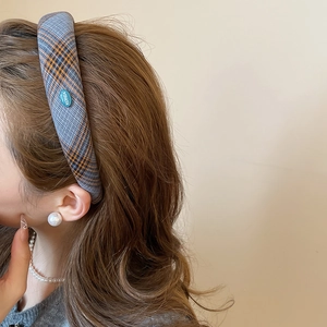 Close-up of grey and orange plaid cotton headband featuring a small blue logo tag