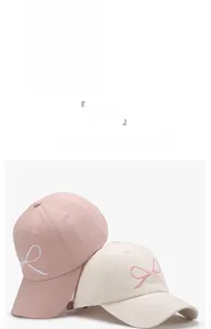 Detail of pink and beige baseball caps featuring delicate bow embroidery and curved brim