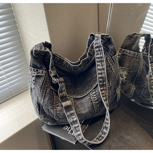 Détail du sac hobo en denim noir délavé avec une texture de tissu déchiré très élégante