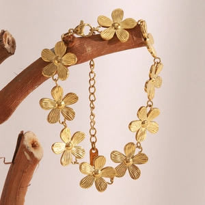 18K gold plated stainless steel daisy flower bracelet hanging on a rustic branch