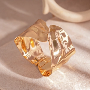 Modern wide irregular hammered gold bangle with hinge closure and lava texture design