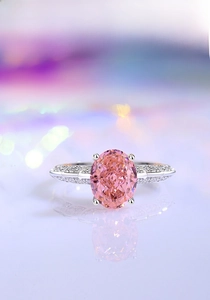 Macro shot of silver ring with oval pink gemstone and shimmering pavé side stones