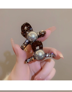 Detail of dark brown hair claws featuring grey faux pearls and sparkling rhinestones