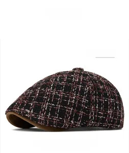 Detail of dark red plaid newsboy cap with wool texture and brown suede brim edge