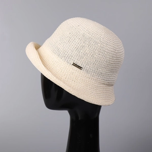 Close-up of cream knit bucket hat with textured roll edge and small gold metal accent