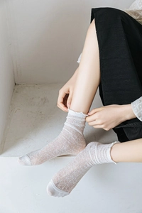 Detailed view of white lace mesh socks with ruffle edges on a female model