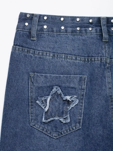 Détail de patchs d'étoiles effilochés et rivets métalliques sur jean bleu large