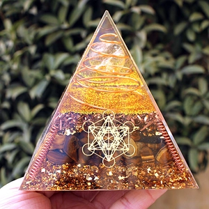 Macro detail of Orgone pyramid with tiger eye stone and crystal ball in resin