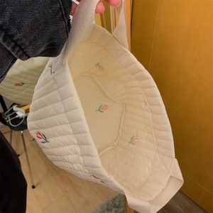 Close-up of quilted storage bag with red tulip embroidery and soft cotton handles
