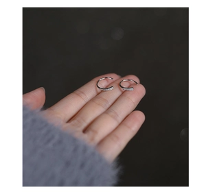 Macro detail of small silver s925 hoop earrings with white zircon on finger for size scale