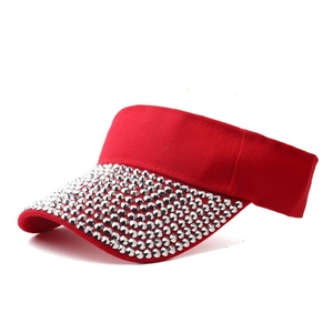 Detailed view of silver rhinestones and rivets on a vibrant red sun visor hat