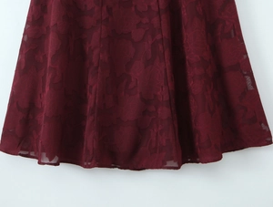 Nahaufnahme von tiefrotem Jacquard-Blumenstoff und Lagen-Saum eines schmalen Kleids