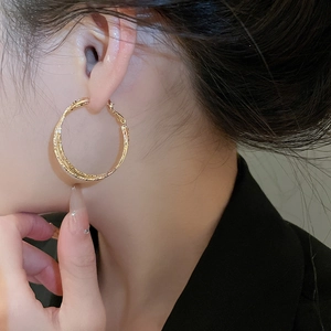 Close-up of double-layered textured gold hoops on model wearing a black blazer