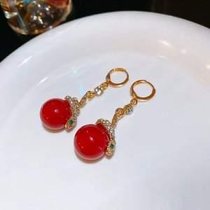 Detail of red floral earrings featuring a gold snake design with sparkling rhinestones