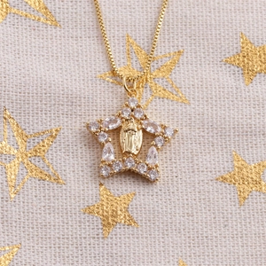 Macro shot of gold star pendant with zircon inlay and Virgin Mary relief on box chain