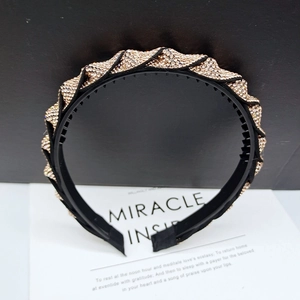 Close-up of wavy black headband with gold rhinestones and non-slip inner teeth