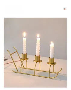 Detailed view of a gold sled-shaped metal candle holder with three spiral white candles