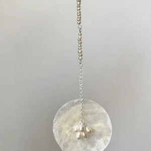 Elegant shell disc earrings with pearl tassels hanging from a minimalist metal hook