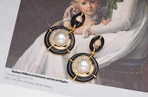 Détail de boucles d'oreilles en émail vintage avec perles et zircons sur un livre