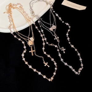 Detail of vintage multilayer cross and pearl necklaces in gold and silver plating