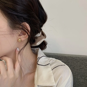 Close-up of minimalist gold bean earrings worn by a model for a chic style