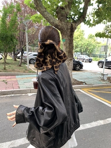 Close-up of leopard print hair scrunchie styled with a black faux leather jacket