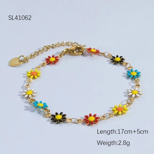 Detail of gold daisy bracelet with colorful enamel flowers and heart charm extender