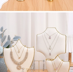 Elegant jewelry on beige velvet stands with gold trim, featuring layered necklaces and earrings