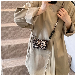 Detailed view of leopard print small crossbody bag with metal buckles and chain strap