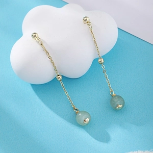 Detail of fan-shaped earrings with gold tassel and translucent light green jade bead