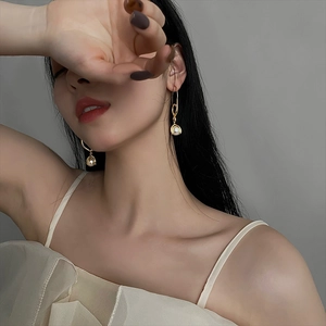French retro gold pearl drop earrings worn by a model against a clean grey background