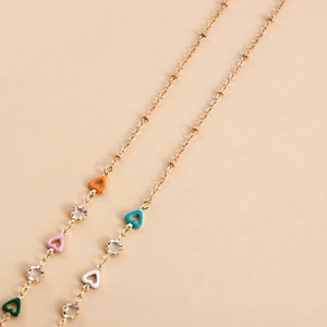 Detail of gold chain with colorful enamel hearts and sparkling crystal accents