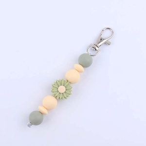 Detail of silicone bead keychain featuring a green daisy and silver lobster clasp
