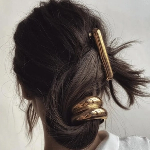 Minimalist gold metal hair clips for women shown on dark brown wavy hair texture