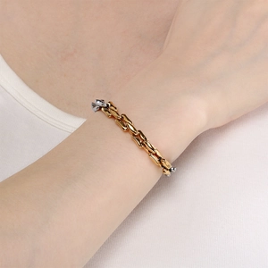 Detalle de una pulsera de cadena gruesa bicolor oro y plata con eslabones planos